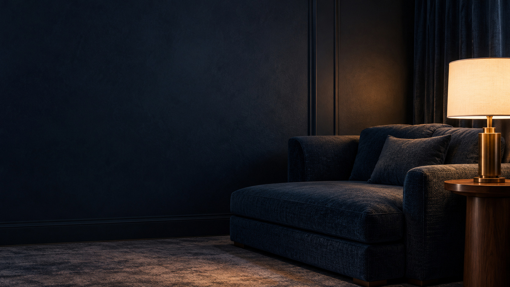 Coin salon d’un hôtel élégant, assise en velours bleu nuit et lampe à lumière chaude.